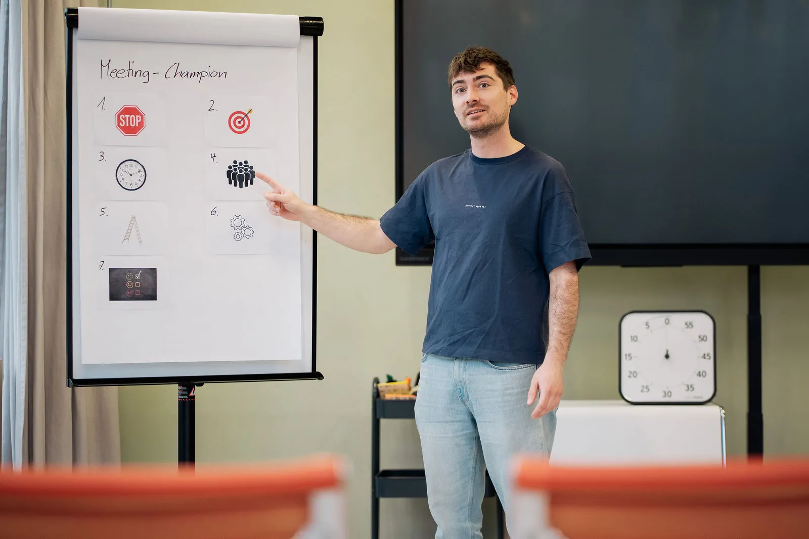 Juan zeigt auf ein Flipchart